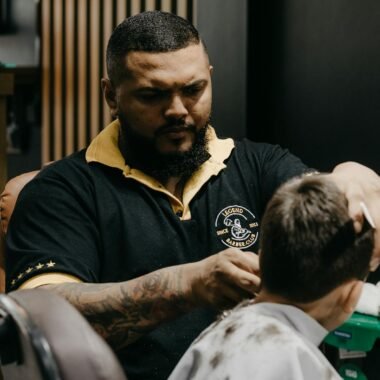 Barber expertly cutting a client's hair in a busy shop. Focus on professional grooming.