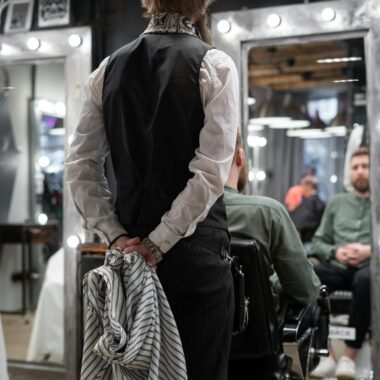 Barber in casual attire with hat and towel preparing for haircut in a trendy barbershop.