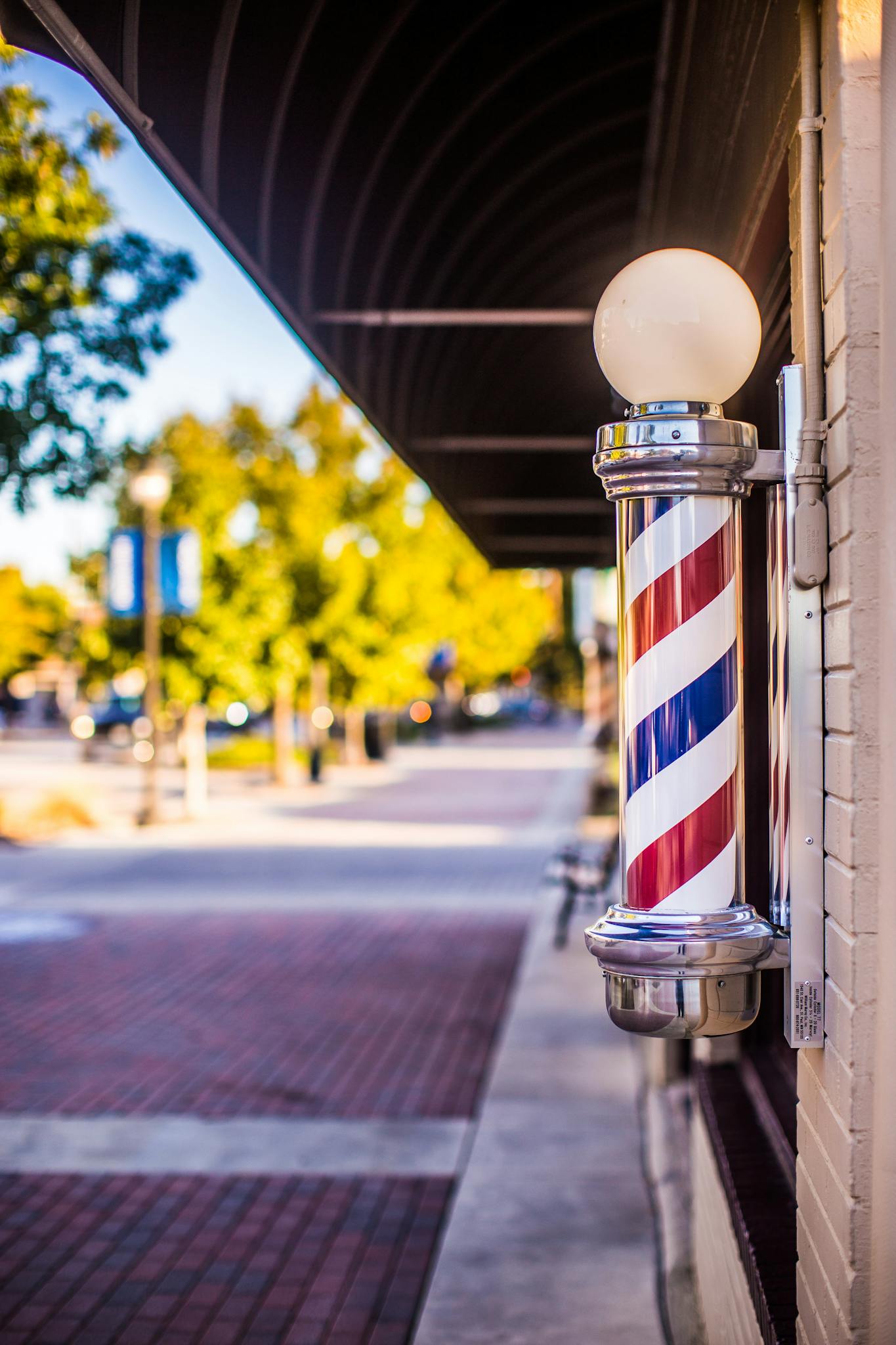 Classic barber pole on a vibrant city street under a sunny sky.
