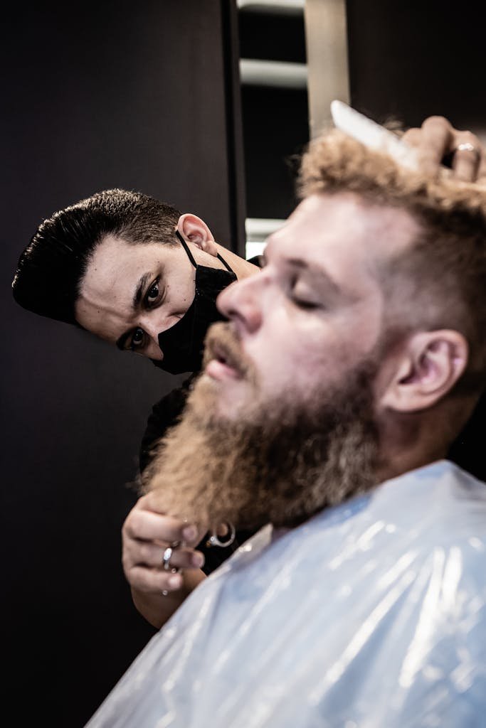 Close-up of a barber skillfully trimming a man's beard at a salon in João Pessoa, Brazil.