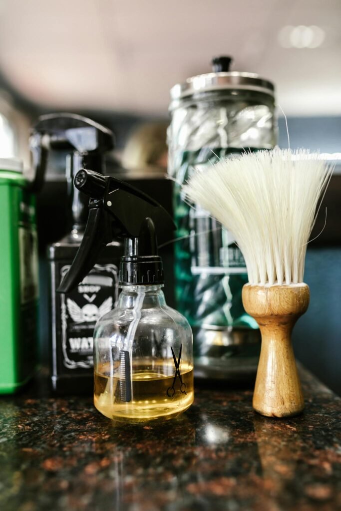 Close-up of barber tools including a brush and spray bottle on a countertop.